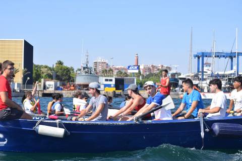 Estudiantes a bordo de un falucho de remo y, detrás, en un dragon boat de piragüísmo.